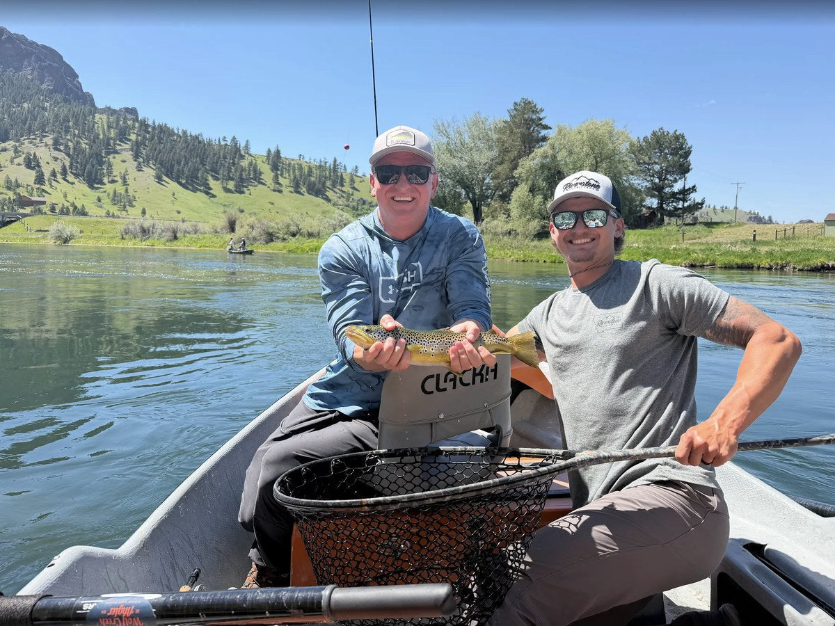 Riverstone Outfitters guide Brendan holding a brown trout with a guest on a Montana river float